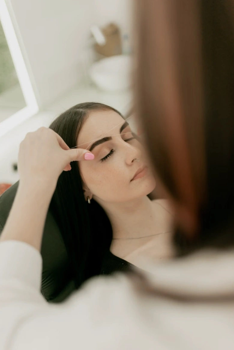 Close view of twisted cotton thread lifting hairs during eyebrow threading